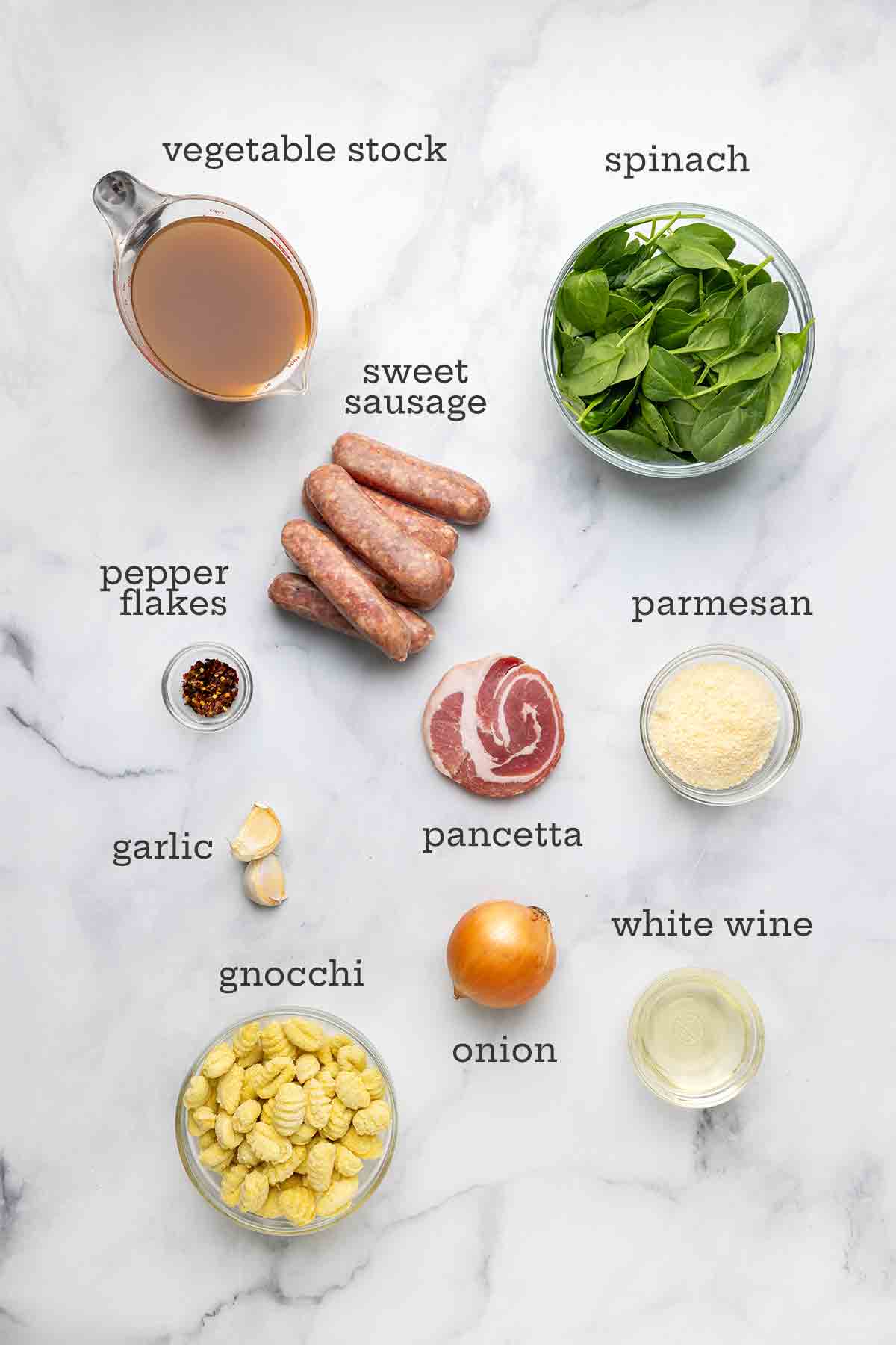 Ingredients for Italian sausage soup--stock, spinach, sausage, pepper flakes, pancetta, parmesan, onion, gnocchi, white wine, and garlic.