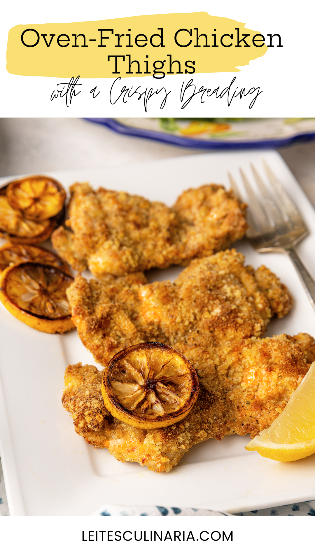 Three breaded chicken thighs on a plate with slices of roasted lemon.