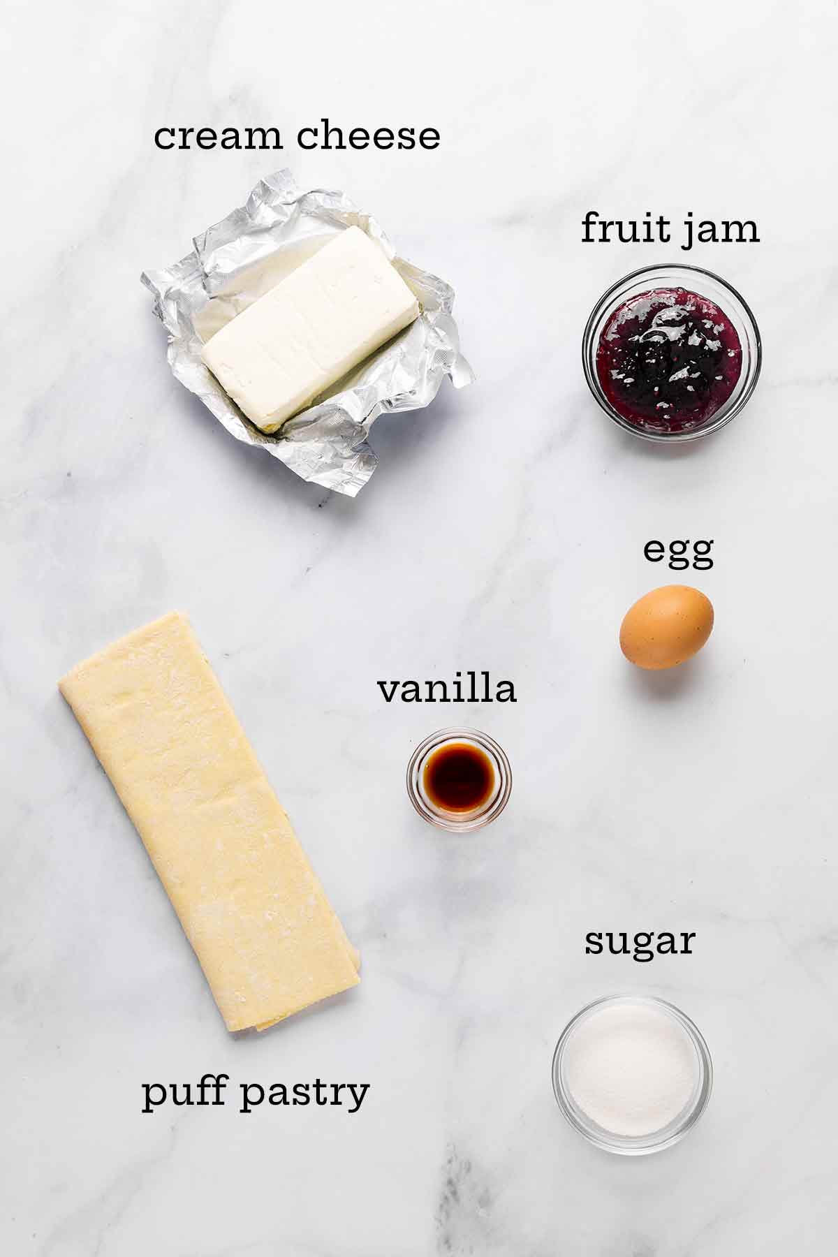 Ingredients for a cheese Danish with fruit filling--cream cheese, puff pastry, vanilla, egg, jam, and sugar.