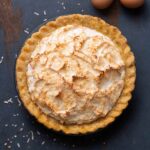 A coconut cream pie with a meringue top and sprinkled with toasted shredded coconut.