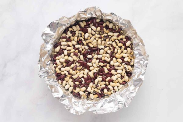 A pie shell lined with foil and dried beans.
