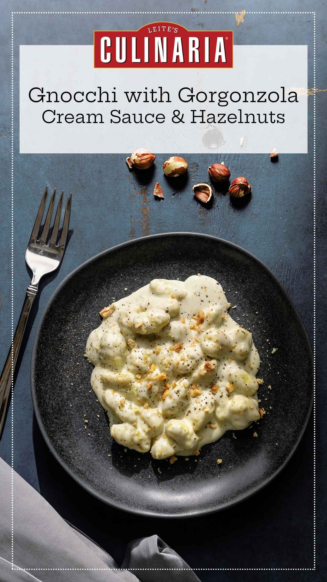 A portion of gnocchi with gorgonzola cream sauce sprinkled with chopped hazelnuts on a black plate.