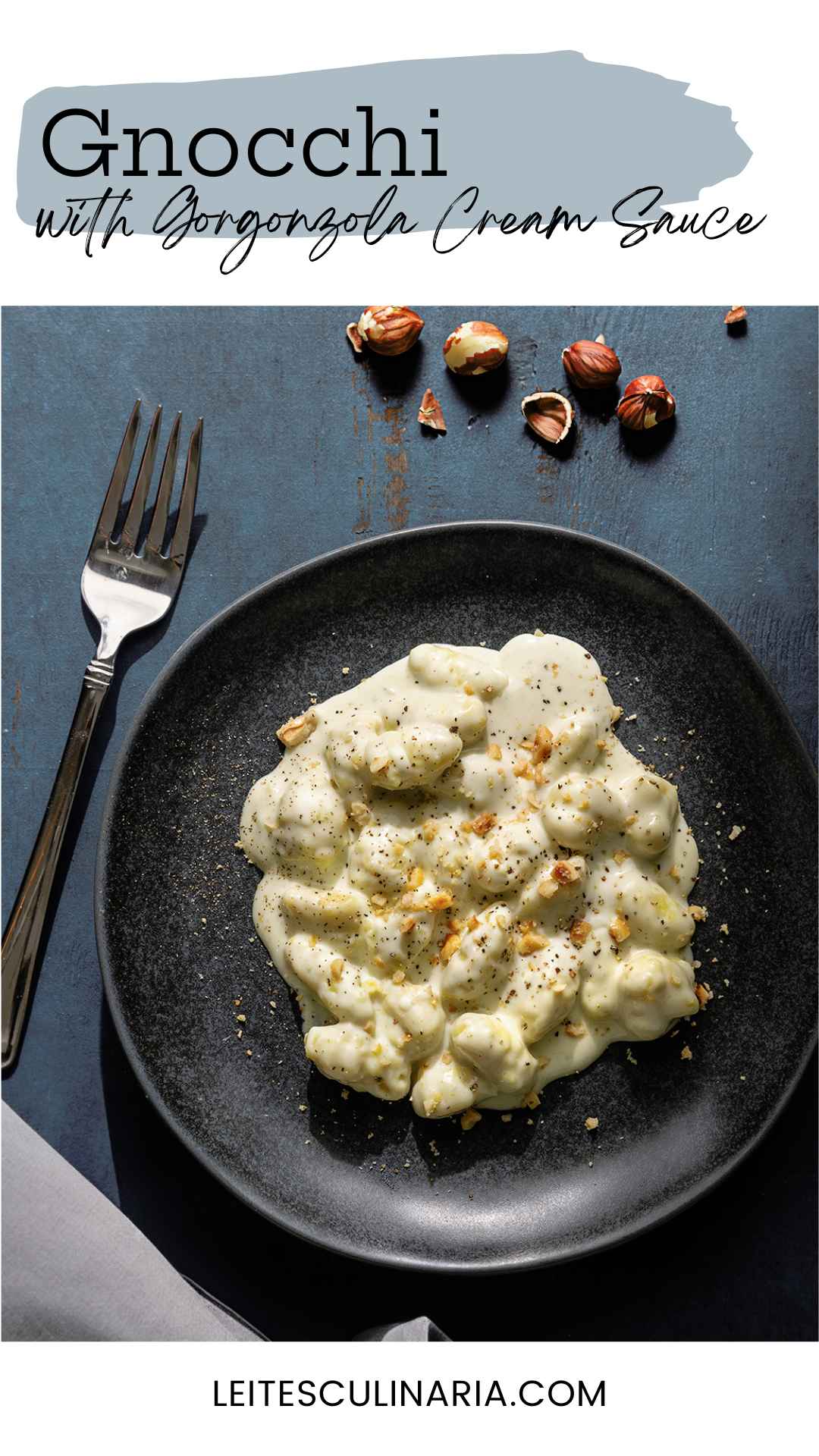 A portion of gnocchi with gorgonzola cream sauce sprinkled with chopped hazelnuts on a black plate.