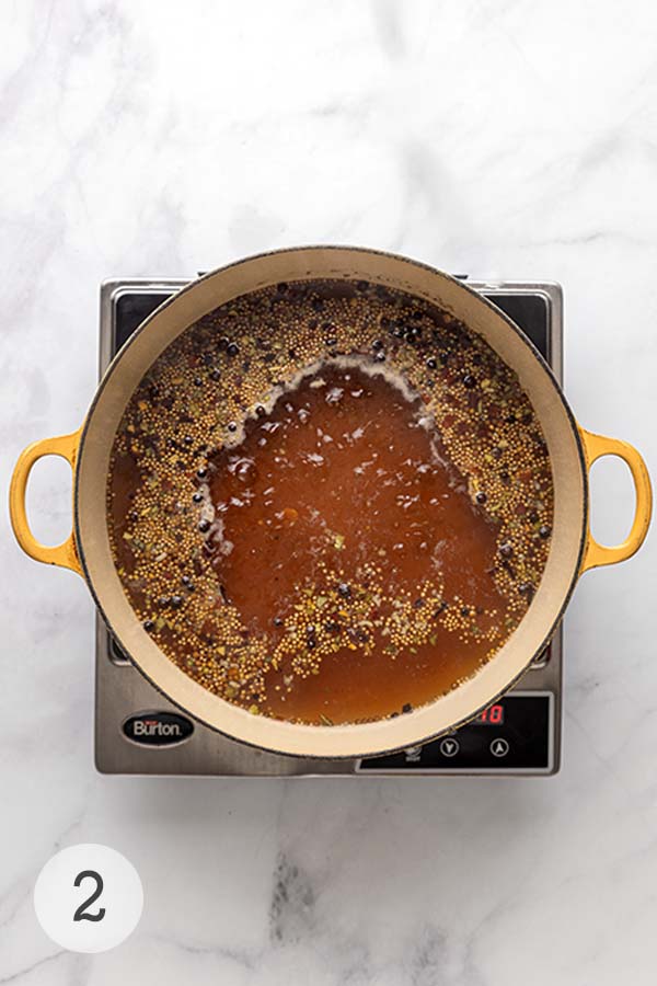 A Dutch oven filled with bubbling corned beef brine, rich with spices and flavor.