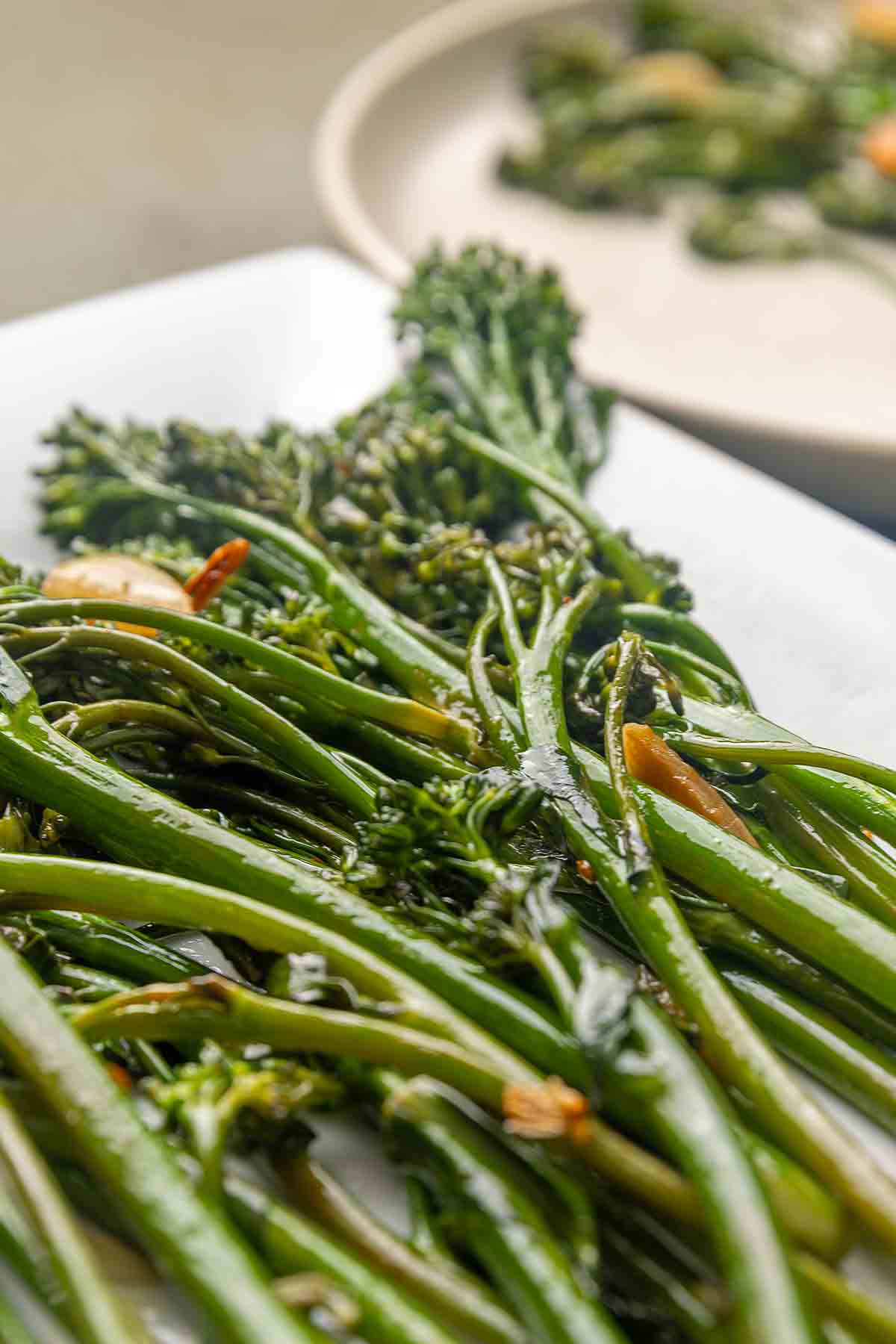 Seared broccolini and slices of browned garlic on a platter.