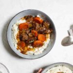 Two bowls filled with mashed potatoes and topped with beef stew.