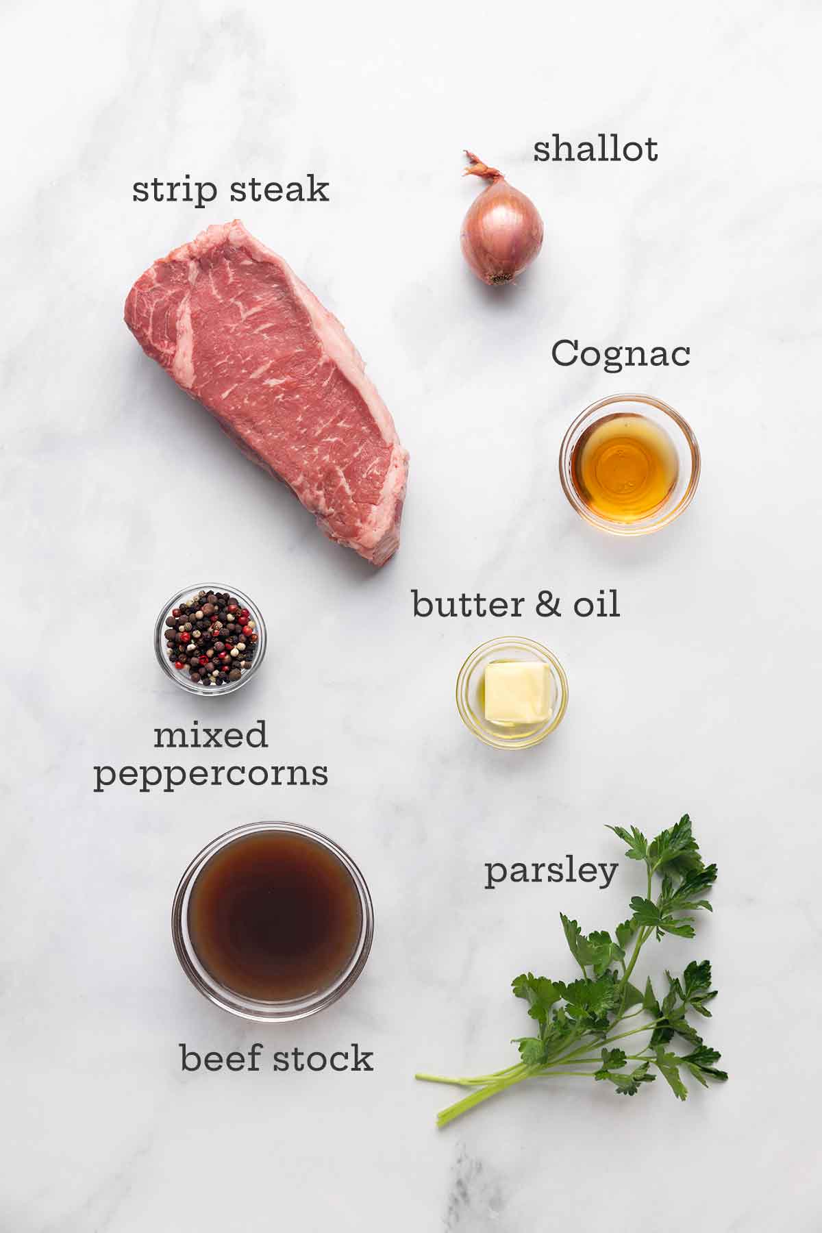 Ingredients for steak au poivre--strip steak, shallot, Cognac, peppercorns, butter and oil, stock, and parsley.
