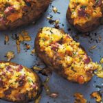 Four twice-baked potatoes with corned beef on a baking sheet.