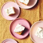 Individual servings of vanilla buttermilk cake with white frosting on pink plates.