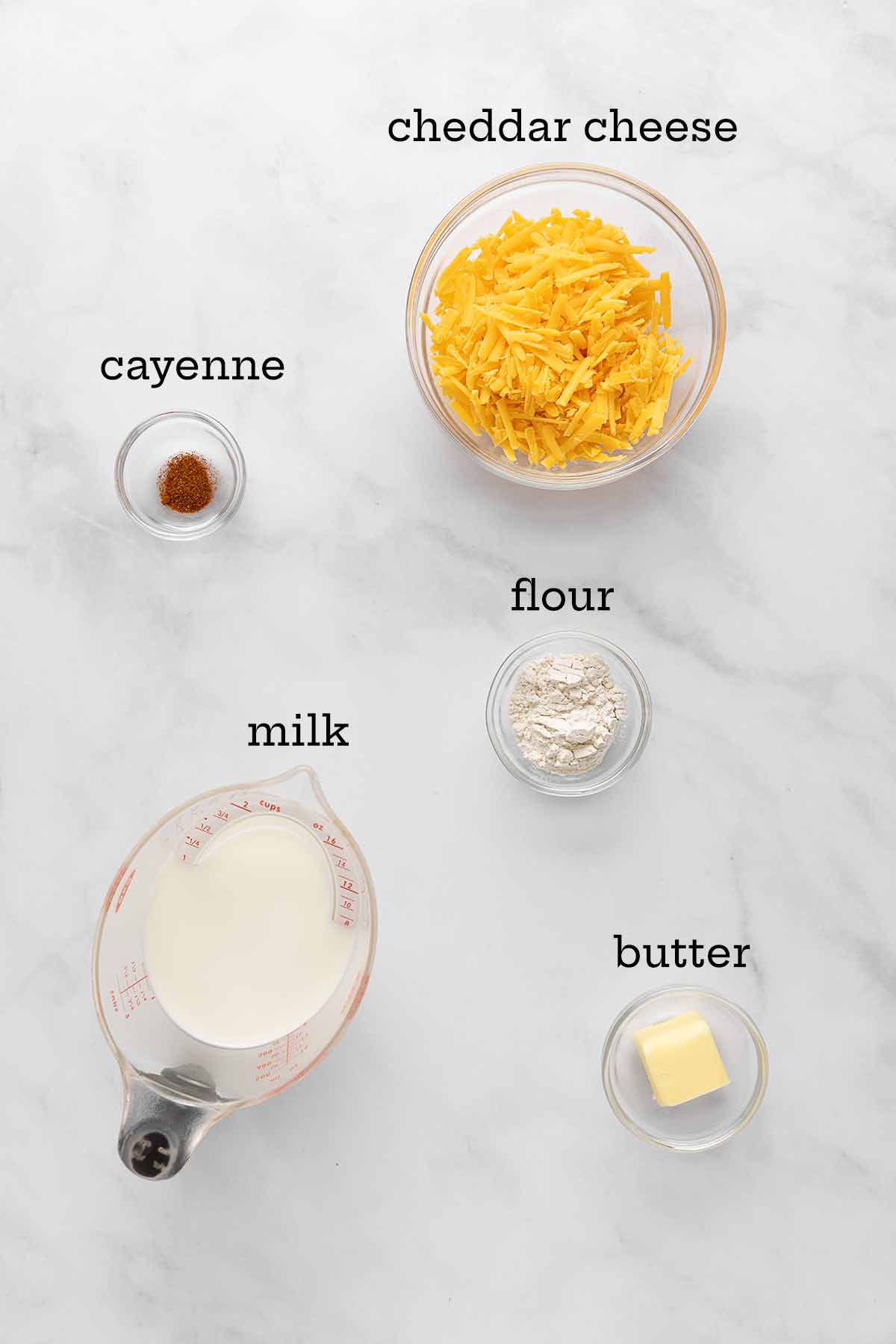 Ingredients for Cheddar cheese sauce--cheese, cayenne, flour, milk, and butter.