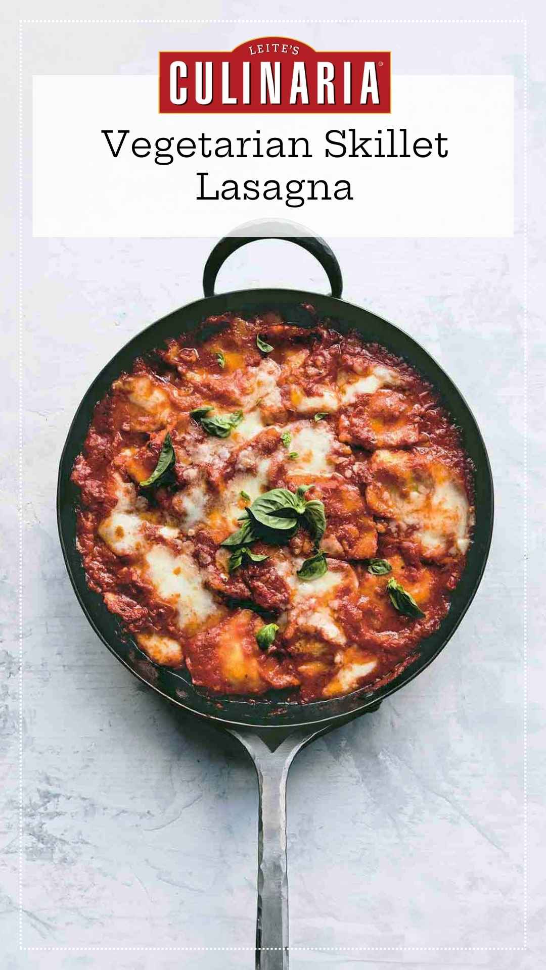 A skillet filled with ravioli in a cheesy tomato sauce with fresh basil leaves on top.
