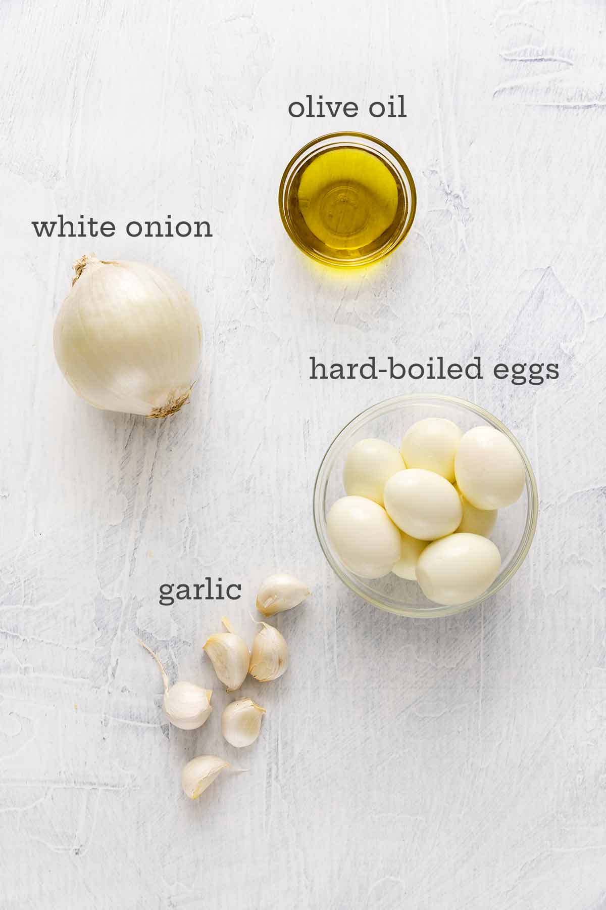 Ingredients for egg salad without mayo--olive oil, onion, garlic, and hard-boiled eggs.