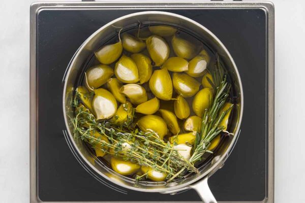 A saucepan of garlic, thyme, and rosemary and olive oil.