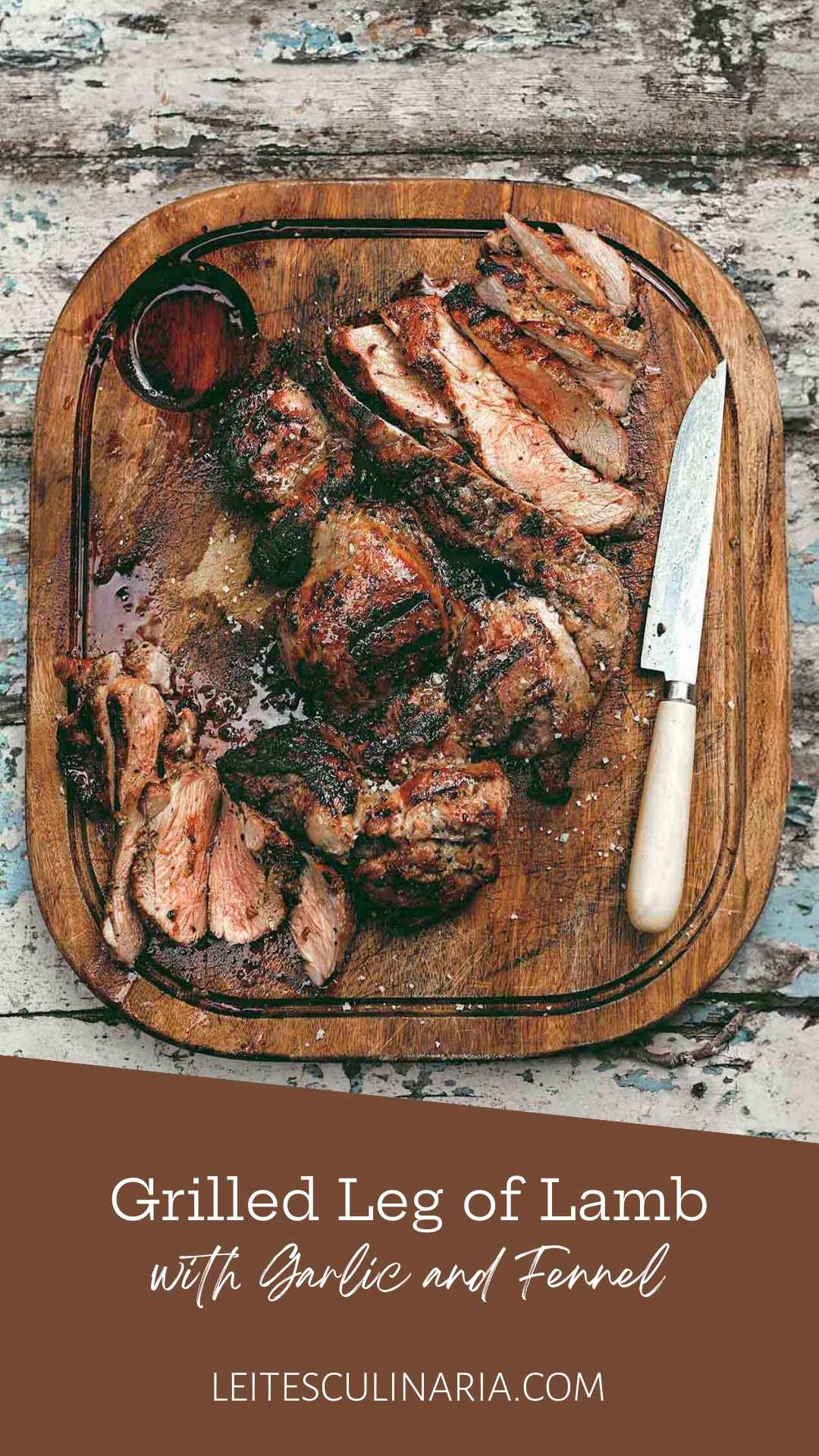 A carved butterflied grilled boneless leg of lamb on a wooden cutting board with a knife resting beside the meat.