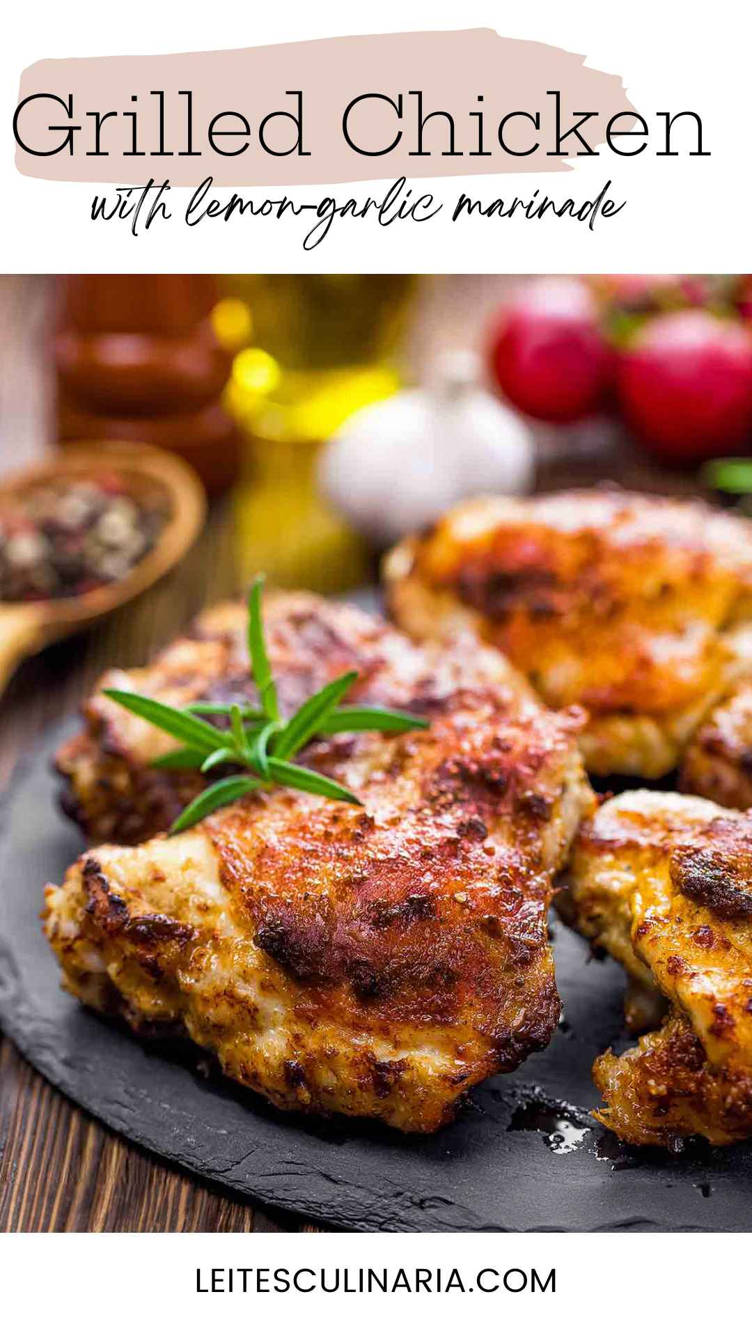 Grilled chicken thighs on a slate platter with a sprig of fresh rosemary on top.