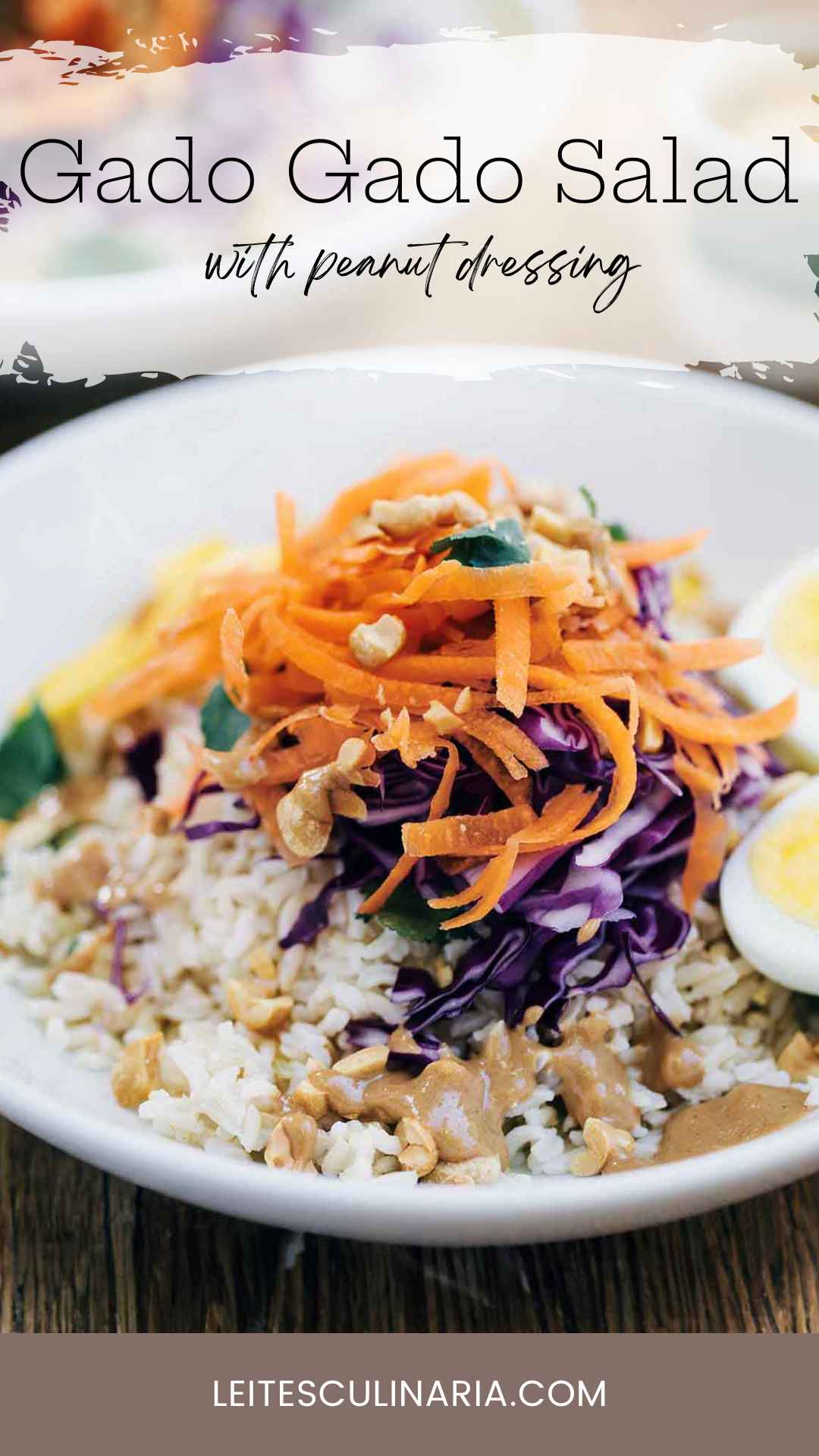 A white bowl filled with gado gado salad with rice, cabbage, carrots, peanuts, egg, and creamy peanut dressing.