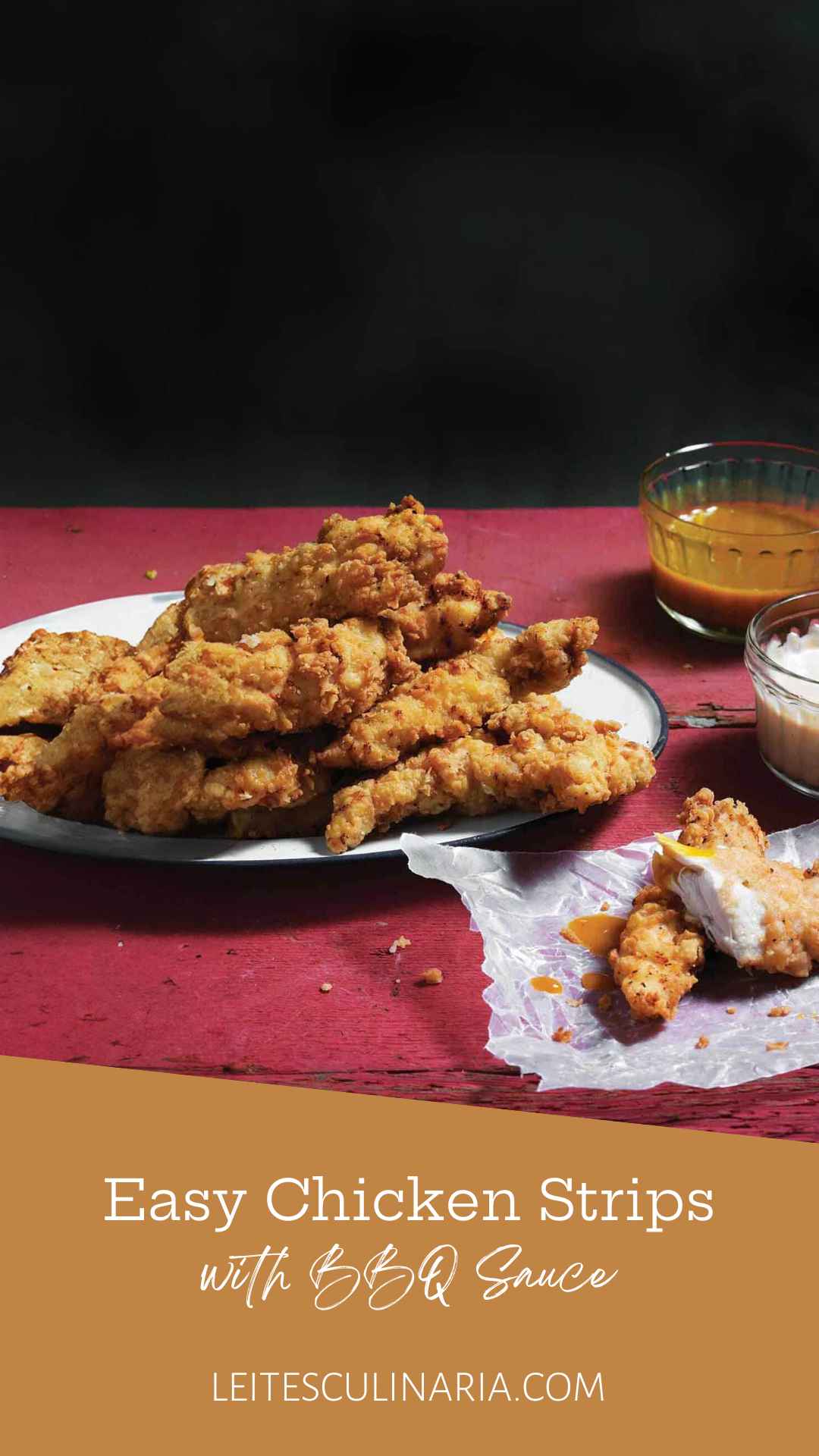 Homemade chicken strips piled on a white plate with dishes of barbecue sauce and ranch nearby.