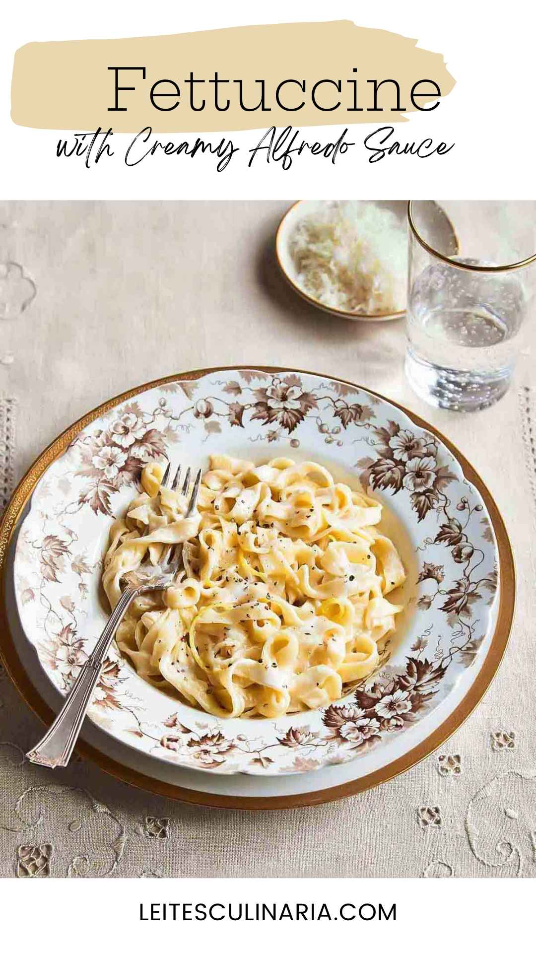 A tangle of fettuccine noodles in Alfredo sauce with lemon zest garnish in a patterned bowl.
