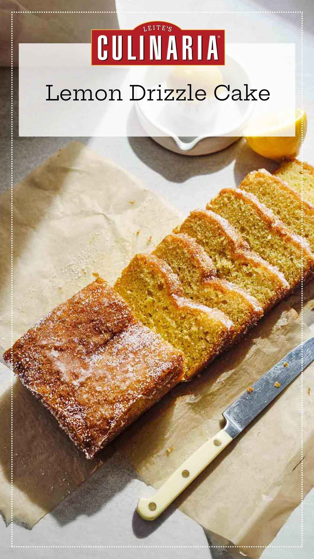 A partially sliced lemon drizzle cake with sugar topping on a piece of parchment paper.