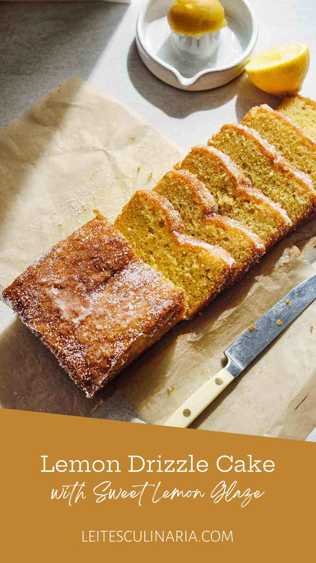 A partially sliced lemon drizzle cake with sugar topping on a piece of parchment paper.