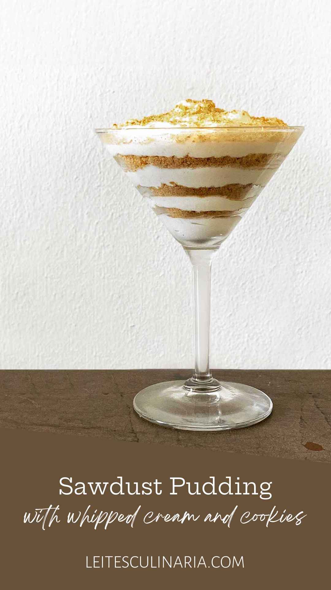 A large martini glass filled with layers of whipped cream and crushed cookies.