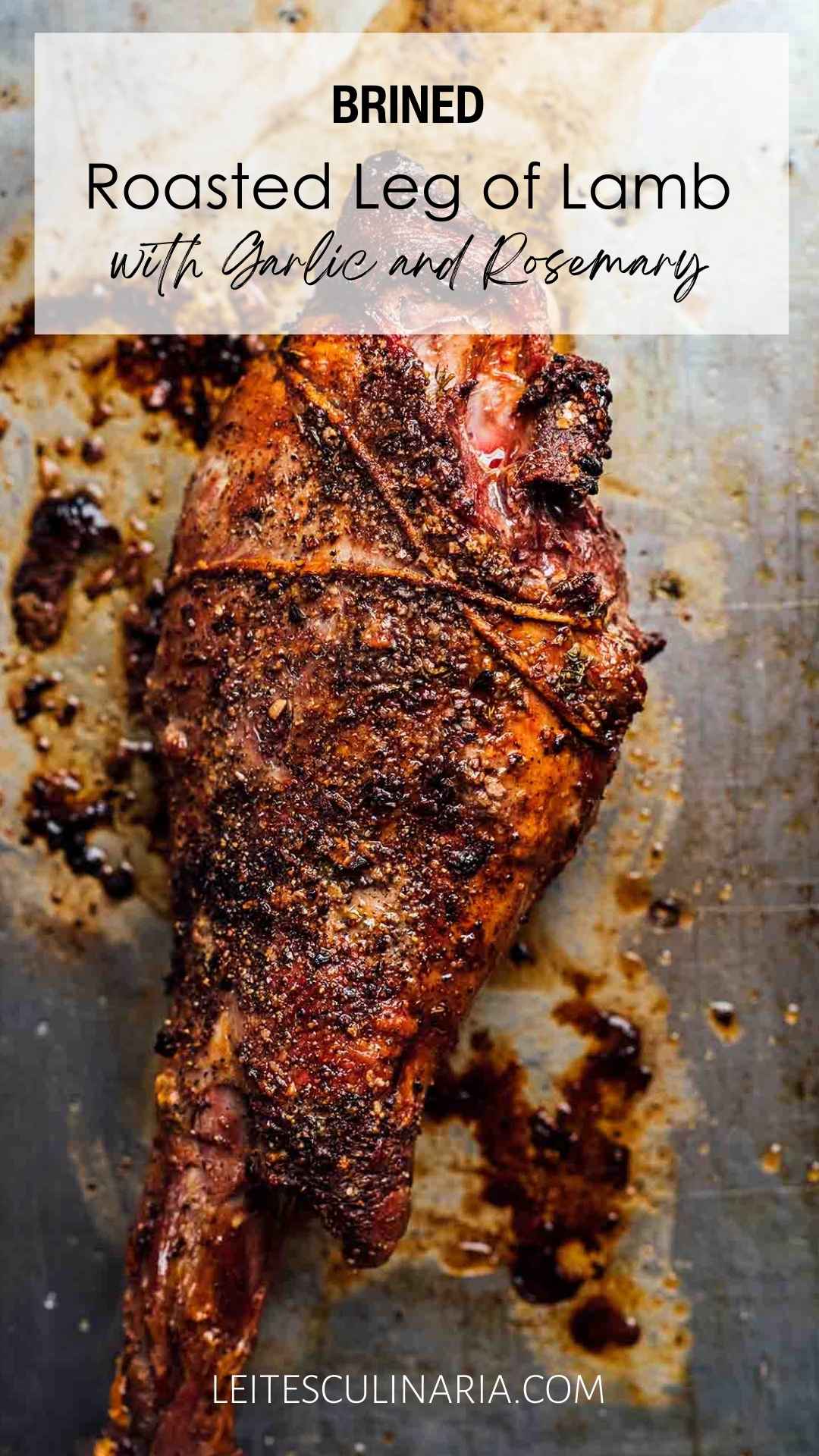 A whole roasted leg of lamb on a baking sheet with a garlic rub.