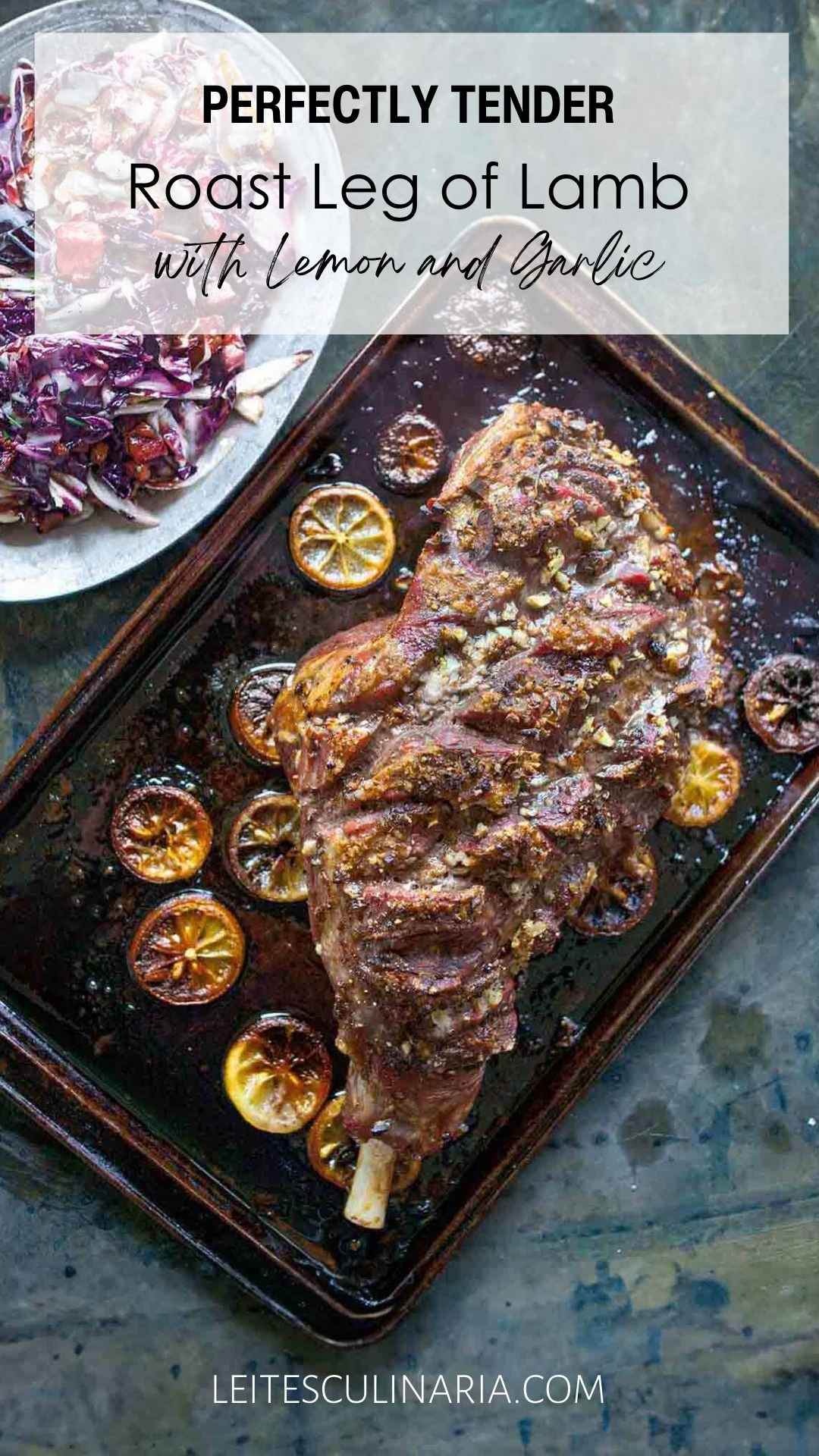 A whole roast leg of lam on a rimmed baking sheet with charred lemon slices scattered around it.