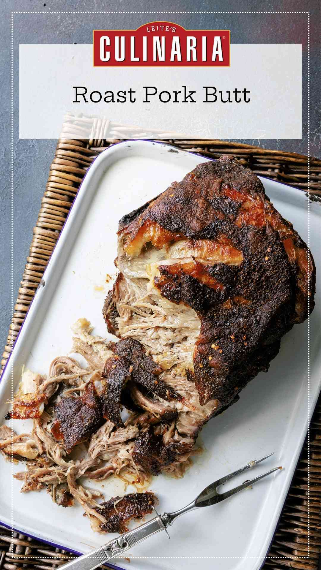 A partially shredded roast pork butt on a white tray.