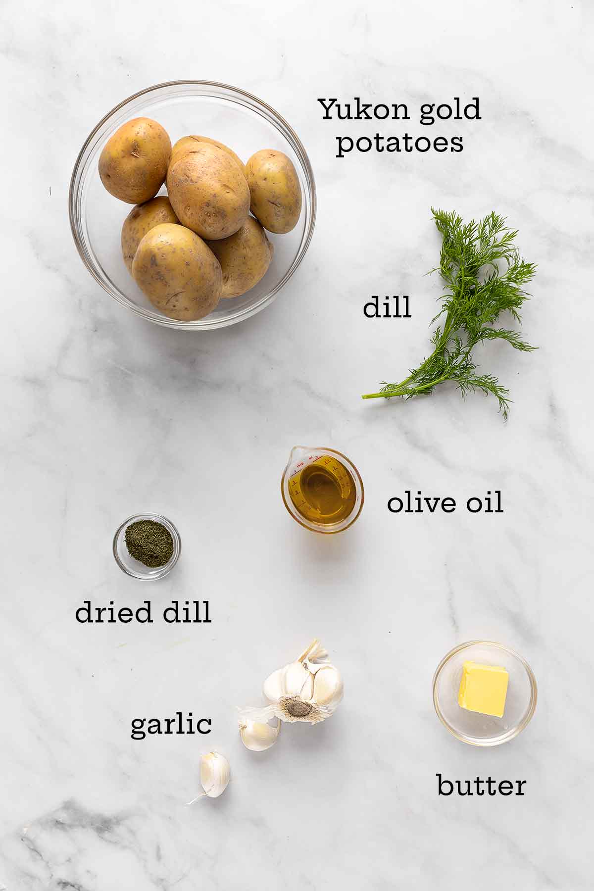 Ingredients for roasted potatoes with dill--Yukon gold potatoes, fresh and dried dill, olive oil, butter, and garlic.