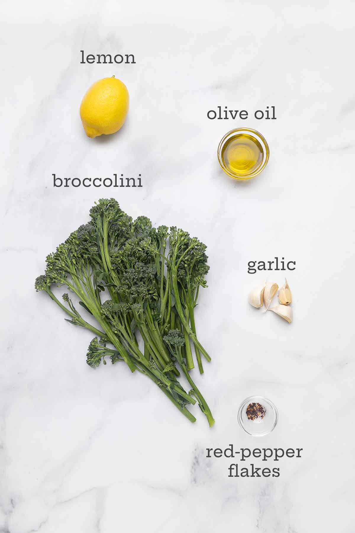 Ingredients for skillet-charred broccolini--broccolini, lemon, olive oil, garlic, and pepper flakes.