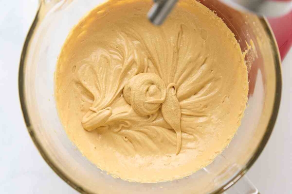Whipped caramel frosting in a glass mixing bowl.