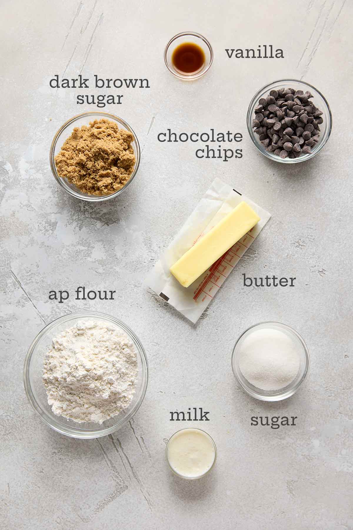 Ingredients for eggless chocolate chip cookie dough--sugar, vanilla, chocolate chips, butter, milk, and flour.