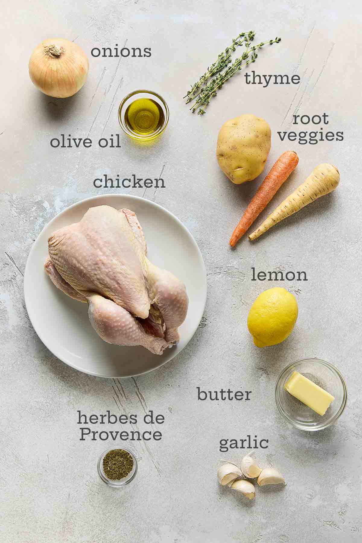 Ingredients for French roast chicken--chicken, onions, root vegetables, thyme, lemon, butter, garlic, and oil.