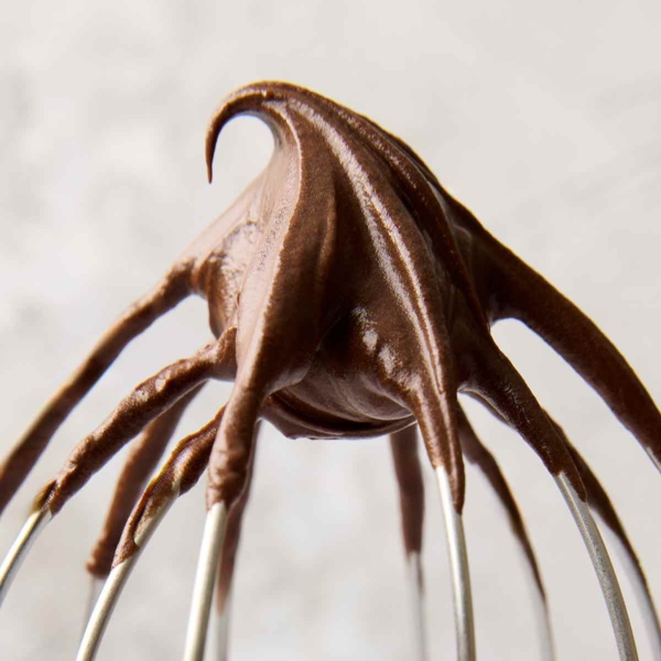 Chocolate frosting on a wire mixer whisk.