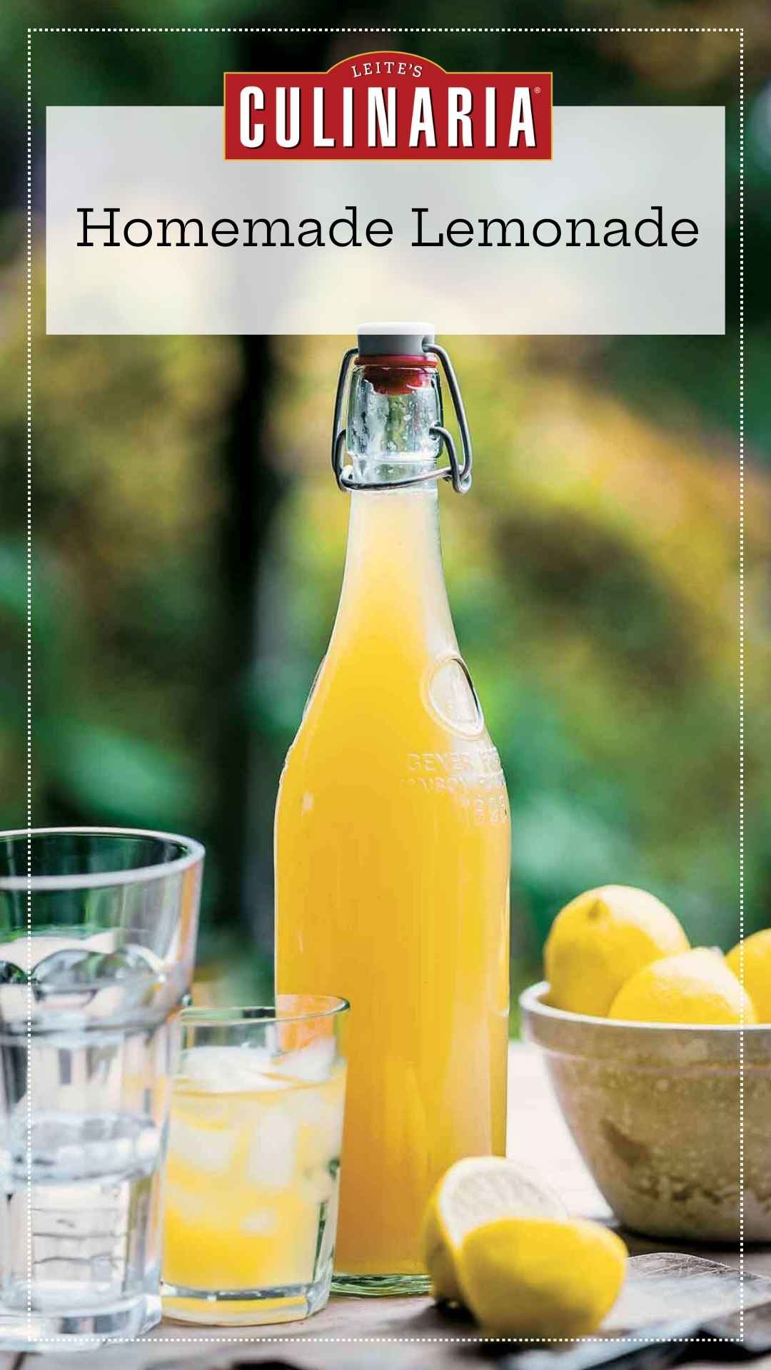 A bottle of lemon syrup with fresh lemons and a glass of lemonade nearby.