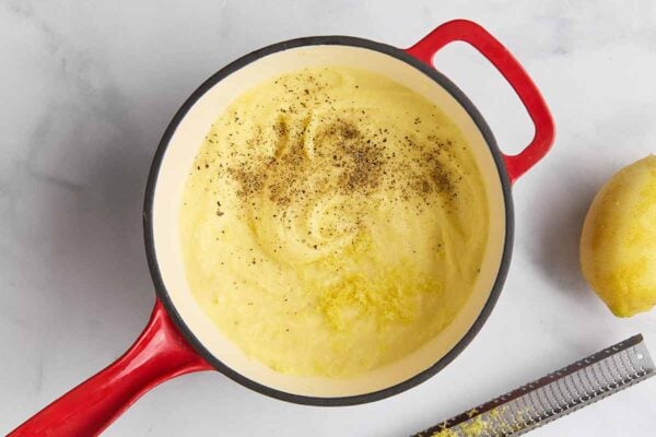A pot of mashed potatoes topped with lemon zest and black pepper.