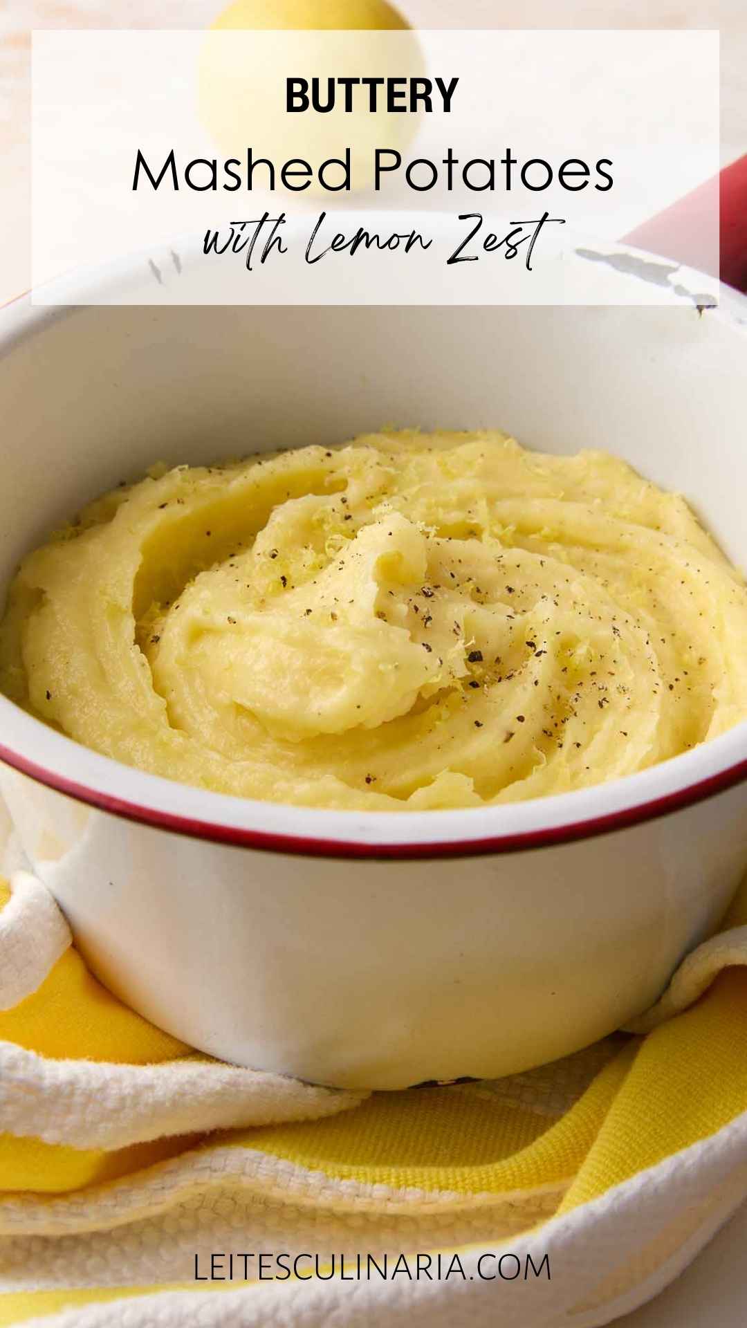 An enamel bowl filled with mashed potatoes, topped with black pepper and lemon zest.