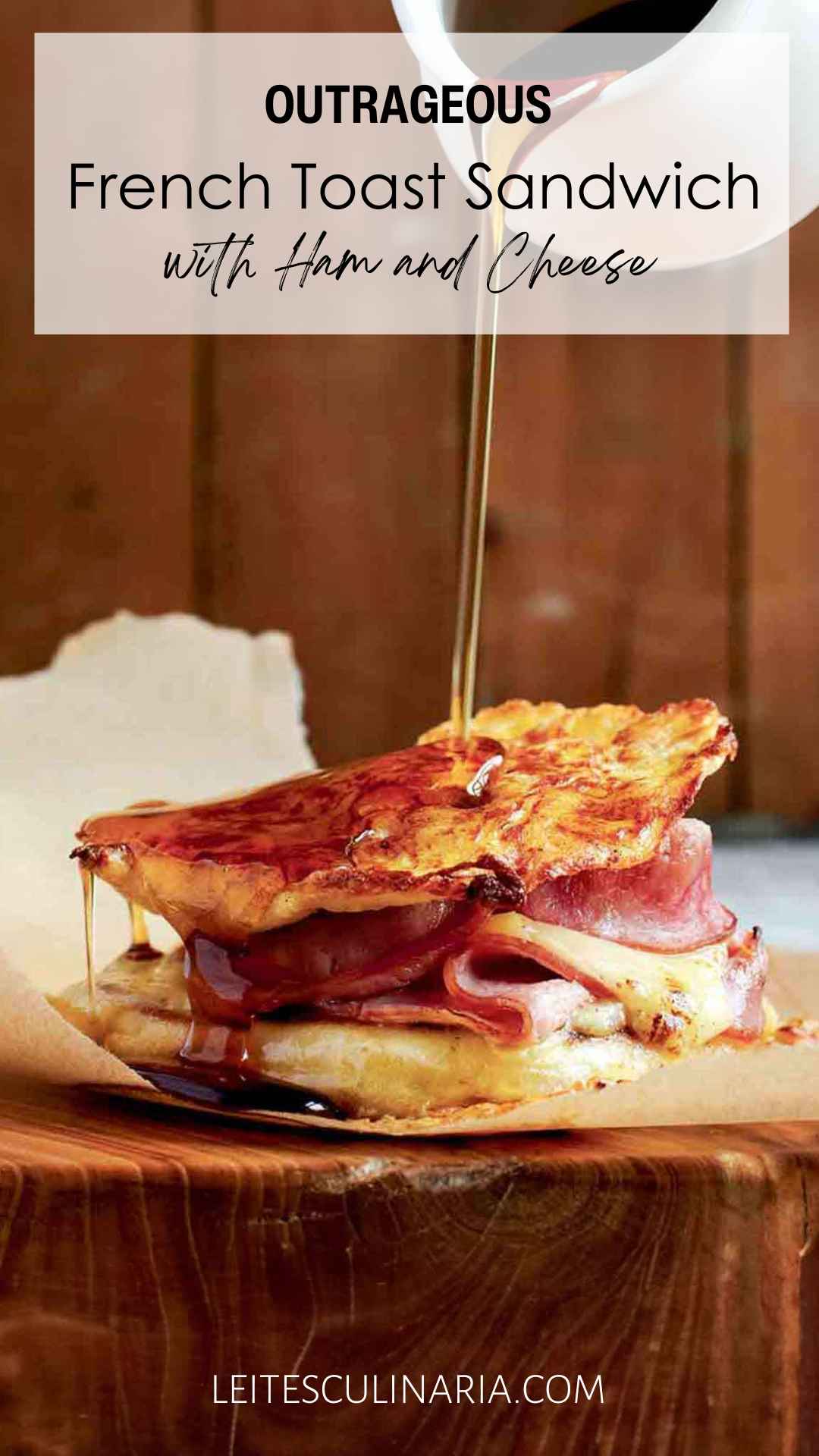 A Monte Cristo sandwich, made with French toast, ham, and Gruyère, with syrup being poured over it.