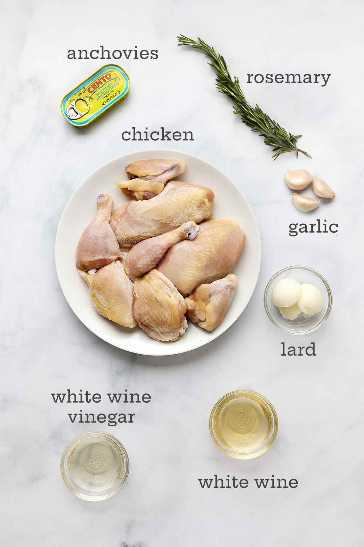 Ingredients for Roman-style chicken cacciatore--chicken, garlic, rosemary, anchovies, lard, white wine vinegar, and white wine.
