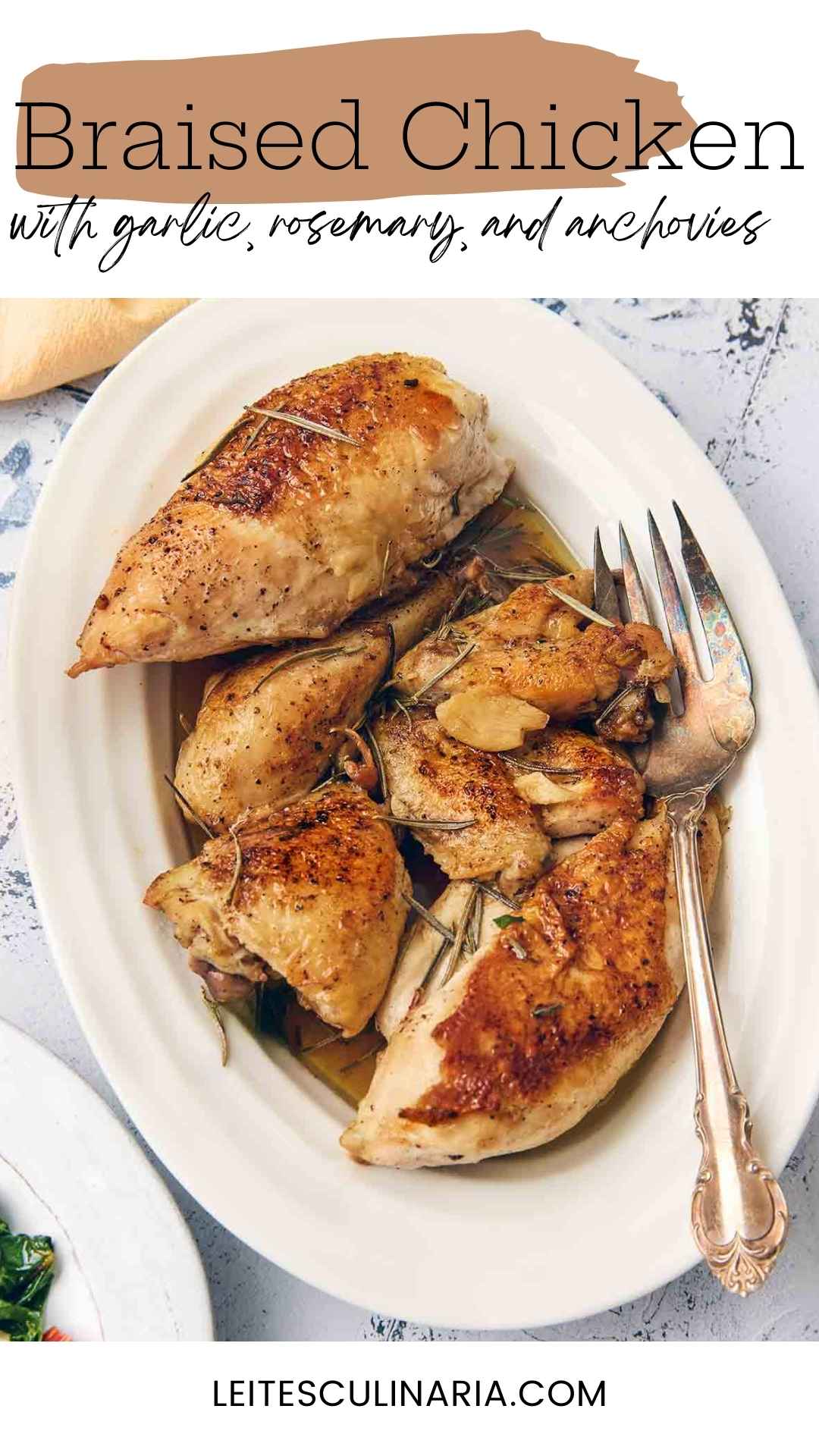 Pieces of browned chicken topped with garlic and rosemary leaves on a white oval platter.
