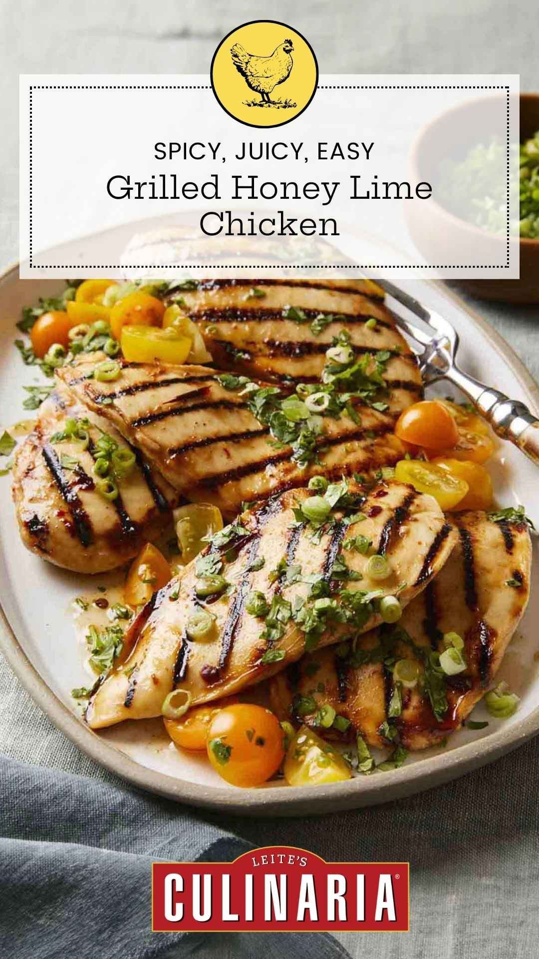 Several grilled chicken breasts on a platter with halved cherry tomatoes and scallions on top.