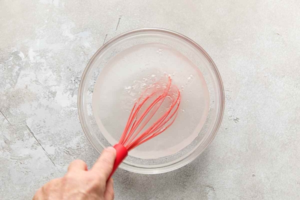 A person whisking a brine solution.