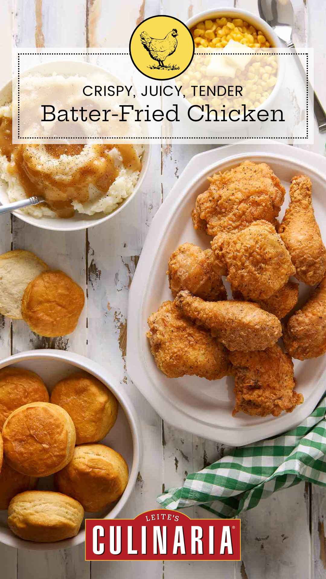 Pieces of batter-fried chicken piled on a white platter, along with biscuits, mashed potatoes, and buttered corn.