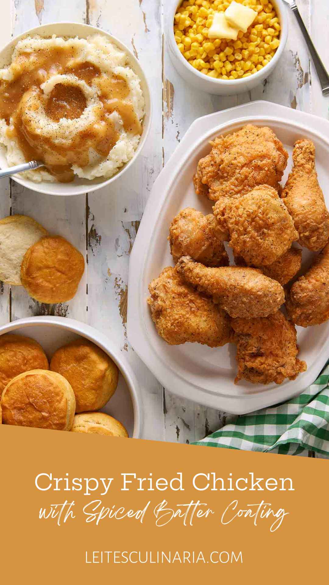 Pieces of batter-fried chicken piled on a white platter, along with biscuits, mashed potatoes, and buttered corn.