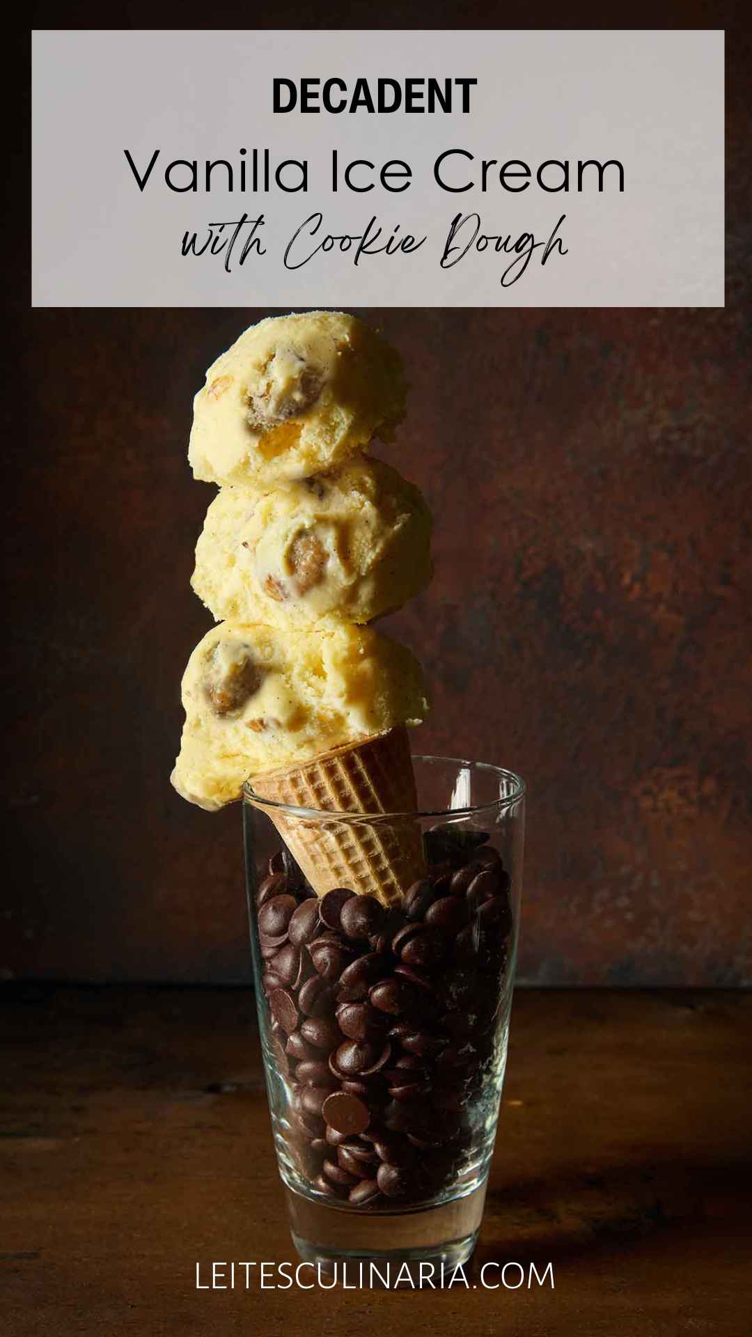 A sugar cone of chocolate chip cookie dough ice cream in a tall glass of chocolate chips.