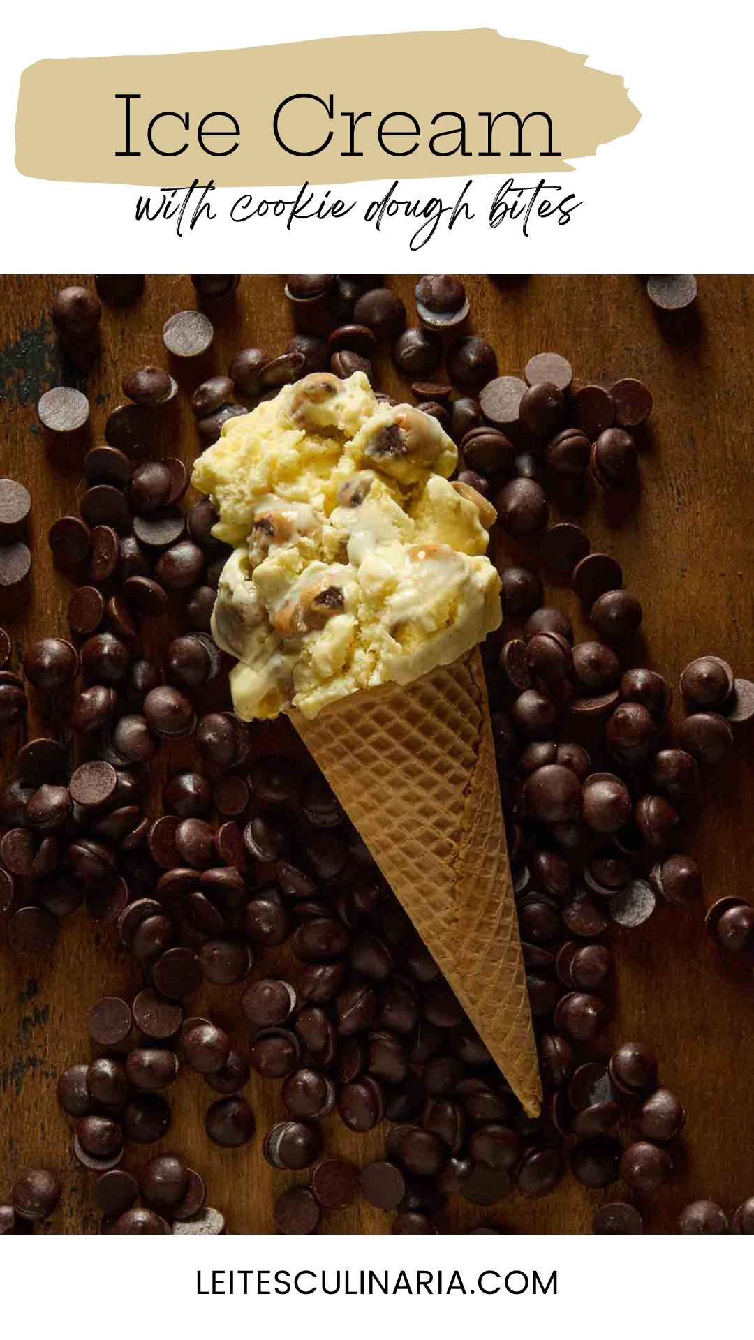 A sugar cone of chocolate chip cookie dough ice cream lying on a bed of chocolate chips.