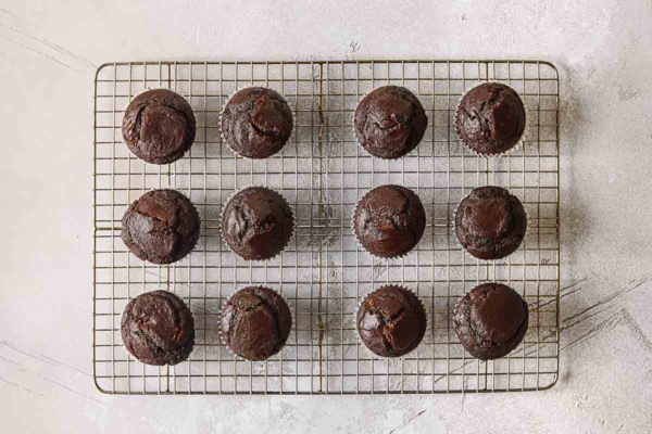 Twelve chocolate muffins cooling on a wire rack.