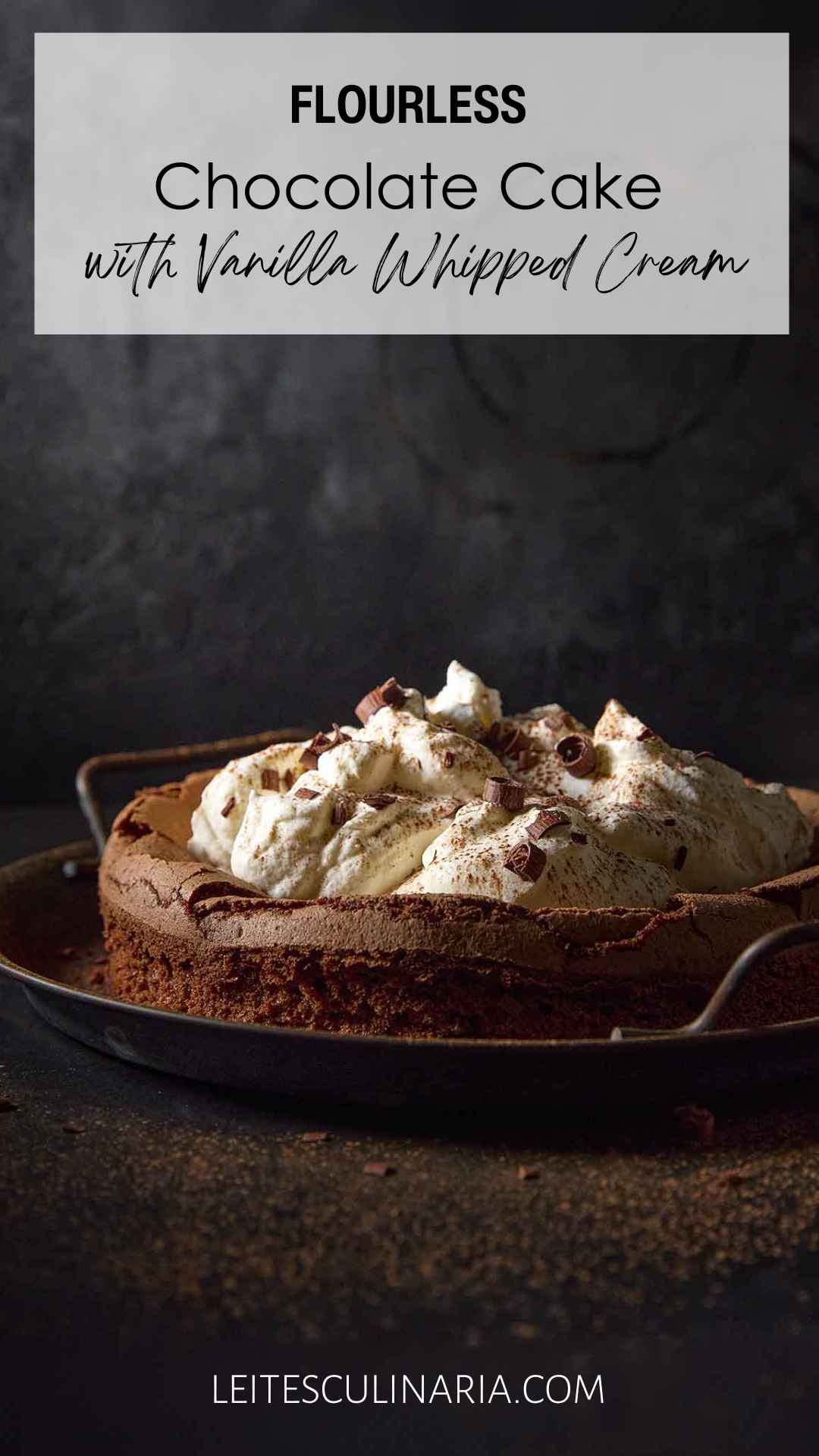 A flourless chocolate cloud cake topped with billows of whipped cream on a metal platter.