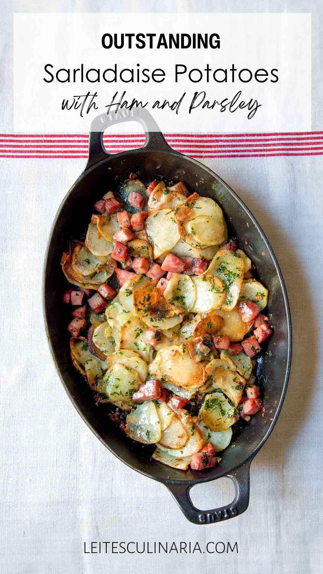 An oval casserole dish filled with cubed ham and thinly sliced potatoes sprinkled with parsley.