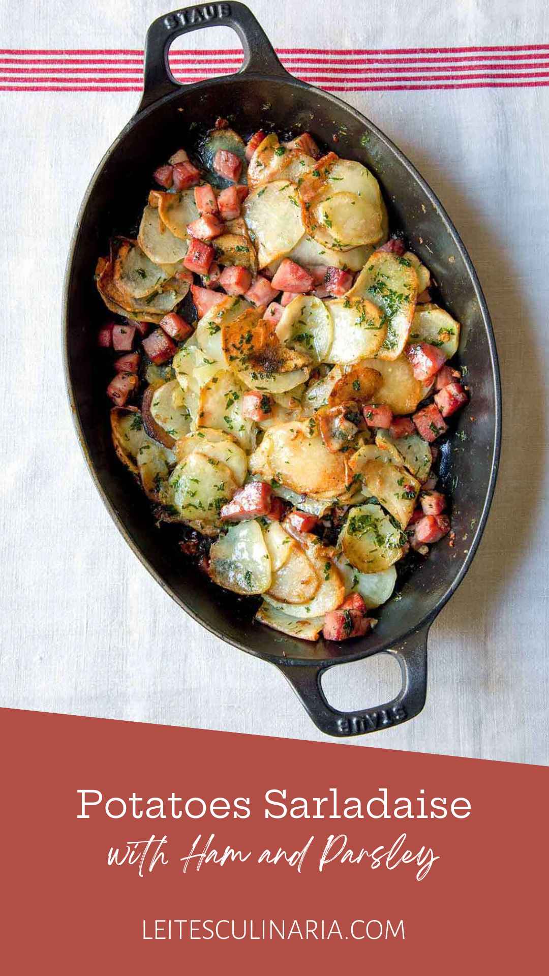 An oval casserole dish filled with cubed ham and thinly sliced potatoes sprinkled with parsley.